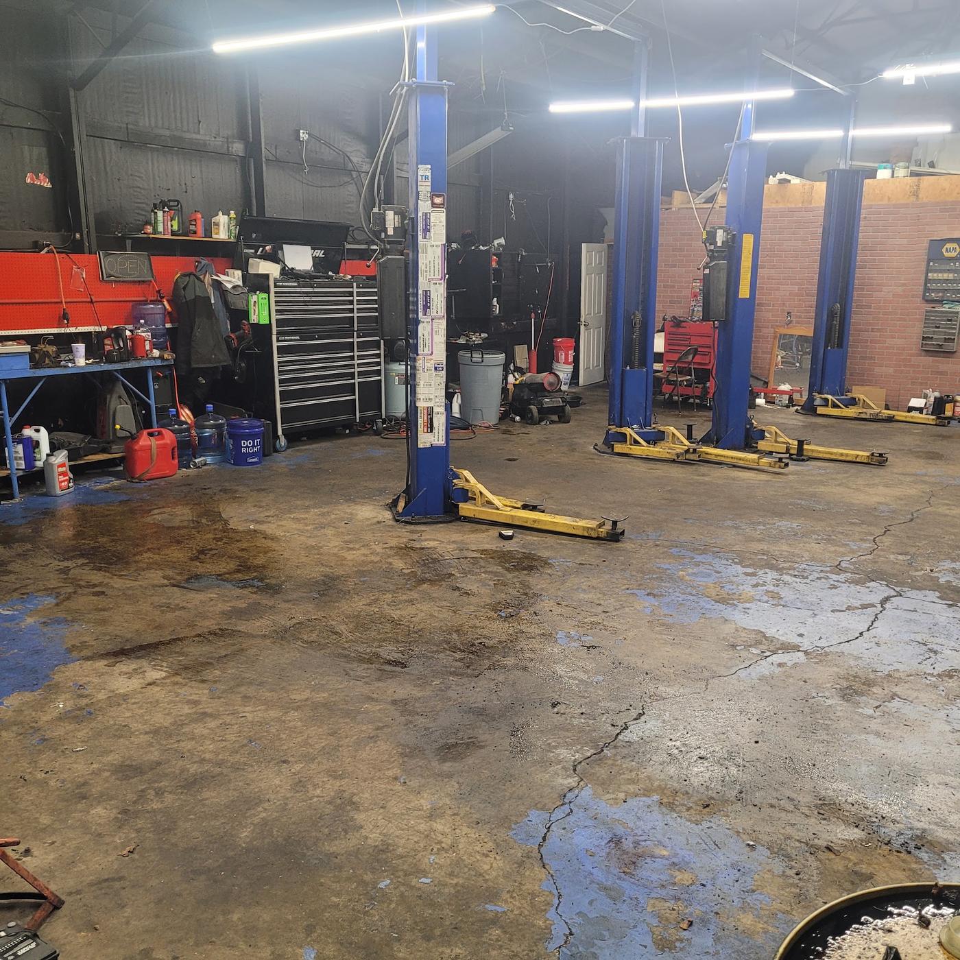The shop floor: lifts, tool chests and the workbench with the OPEN sign