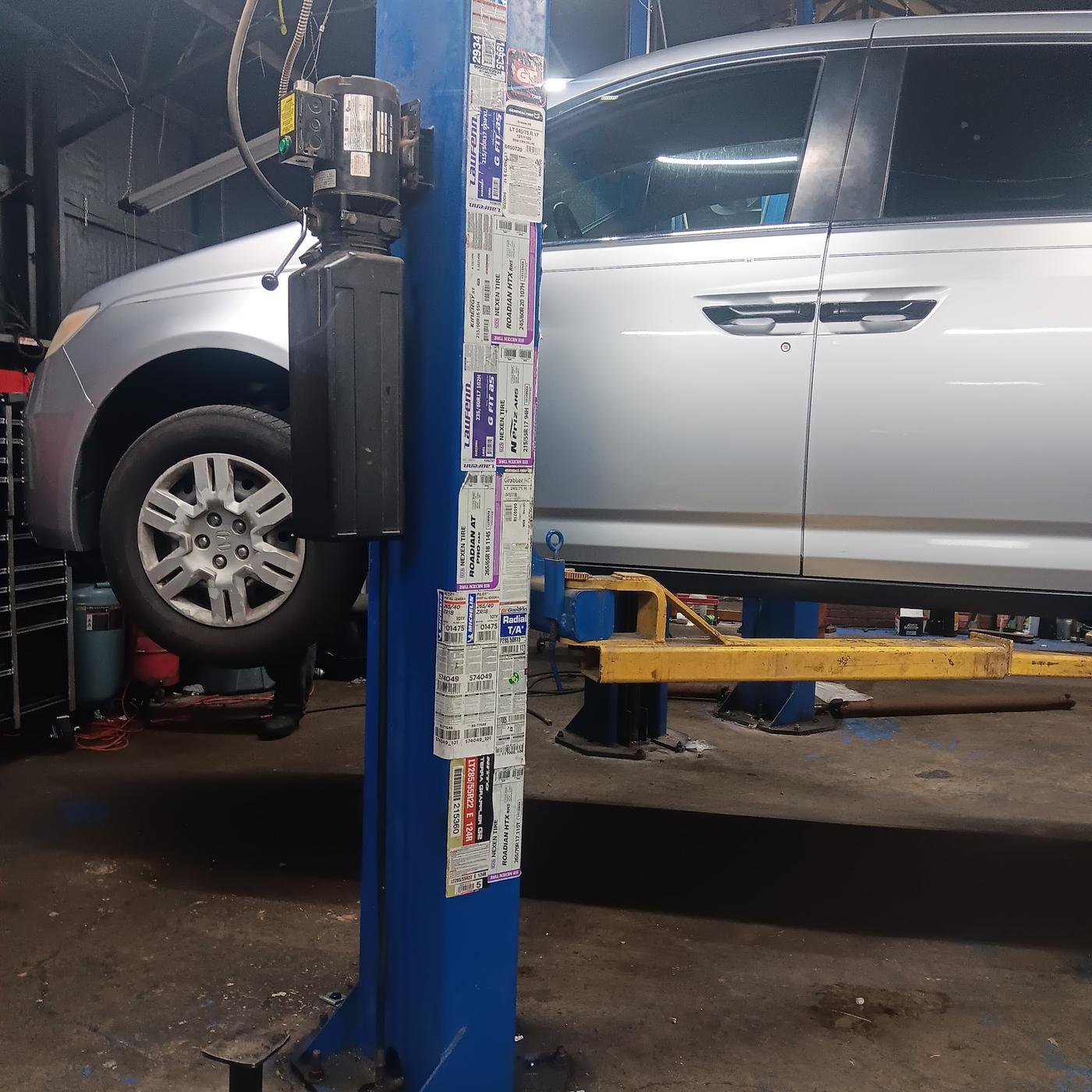 A silver minivan up on the two-post lift in the shop